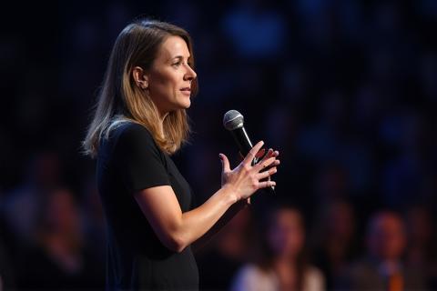 Person speaking confidently at a microphone during a public event.